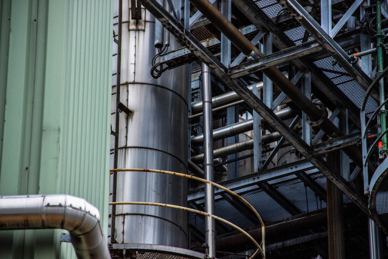 Services Close-up of an industrial metal structure with pipes and steel framework seen outdoors.