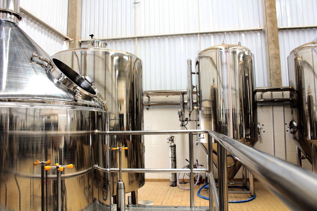 Services A view of stainless steel tanks in a modern brewery, showcasing industrial machinery and production equipment.